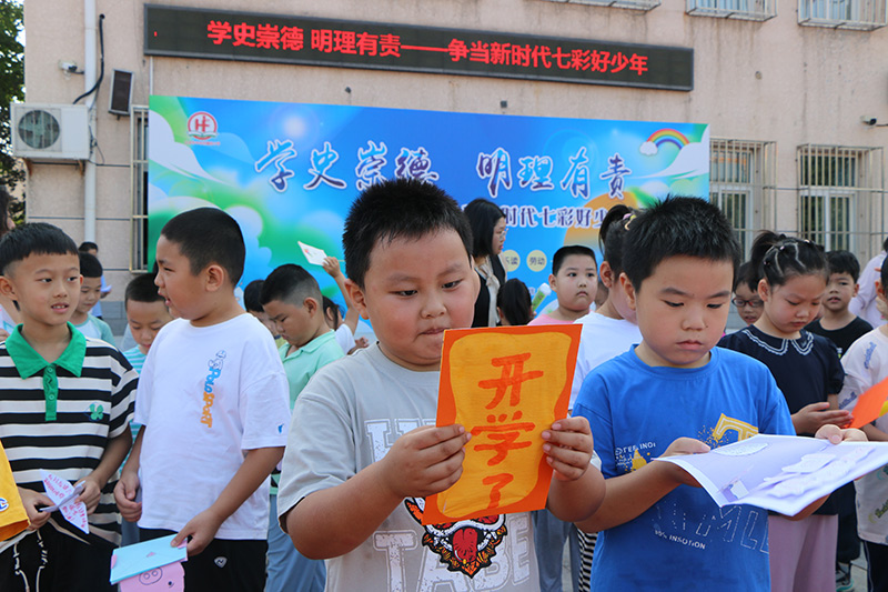 9月1日，北京市豐台區槐房小學組織召開新學期開學典禮。圖為一年級的小學生認真觀看高年級的哥哥姐姐送給他們的歡迎賀卡。北京市教委供圖