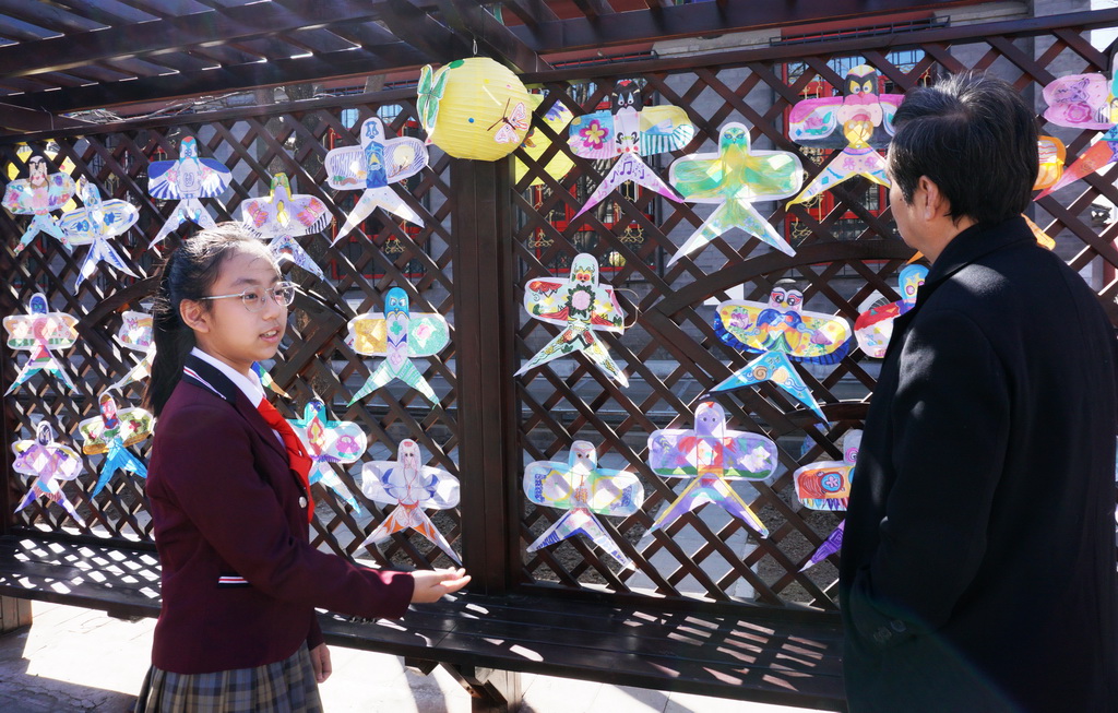 3月24日，府学胡同小学学生向来宾介绍同学们绘制的风筝。