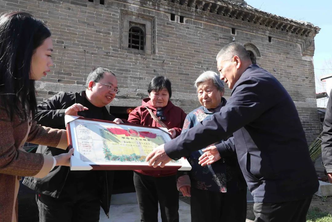 河南省许昌市建安区袁庄，曹明（左二）将修复好的革命烈士证明书交到袁松鹤烈士的家属手中。