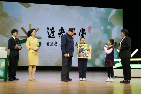平谷六小版画社团的学生代表赠送手工作品《平谷彩韵》，展现了平谷桃花海美景。
